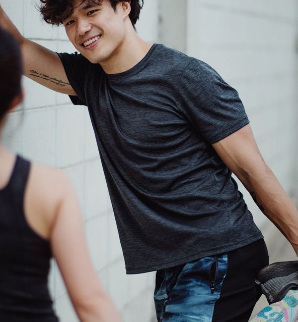 A man smiling and stretching outdoors, feeling refreshed after a workout.